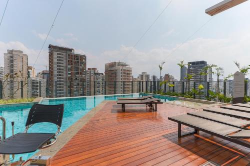 een dakterras met picknicktafels en een skyline van de stad bij 360 Soma Perdizes in Sao Paulo
