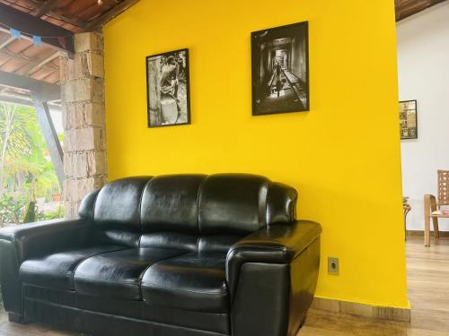 a black leather couch sitting in a room with a yellow wall at Pousada Recanto da Chapada in Mucugê