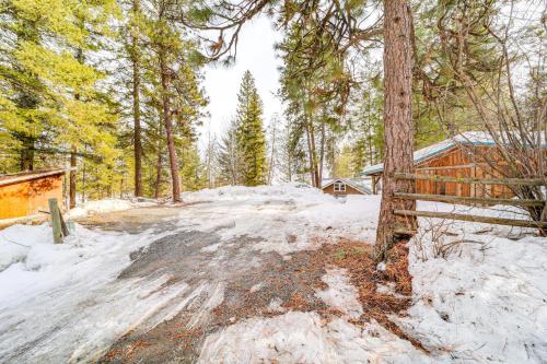 a snow covered road in a forest with a cabin at Chelan Mountain Retreat Chalet with Fire Pit! in Chelan