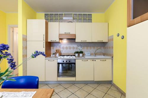 a kitchen with yellow walls and white cabinets at Italian Experience - Sea Suite in Porto Recanati