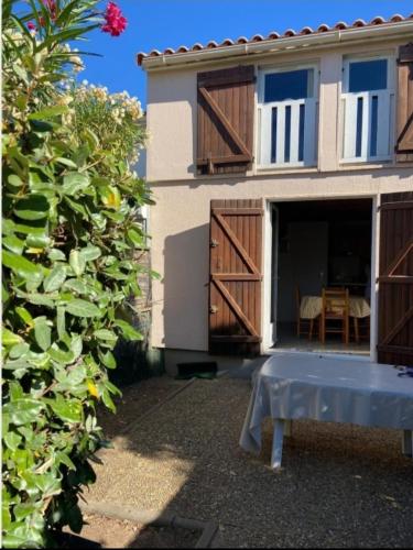 une maison avec des portes en bois et une table devant elle dans l'établissement Maison totalement renovée à Marseillan - 6 couchages - près de l'étant de Thau, à Marseillan