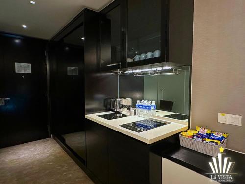 a kitchen with black cabinets and a sink at The Shore Hotel & Residences By Lá VISTA in Melaka