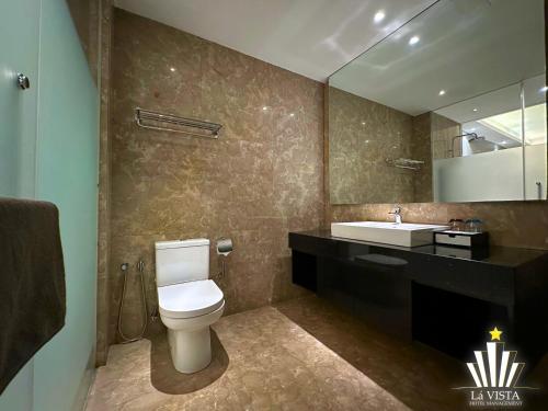 a bathroom with a toilet and a sink and a mirror at The Shore Hotel & Residences By Lá VISTA in Melaka