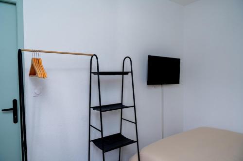 une étagère noire à côté d'un lit blanc dans l'établissement Goodvibes Villeurbanne, à Villeurbanne