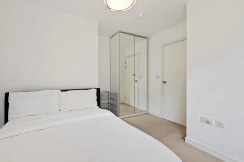 a white bedroom with a bed and a mirror at London Dockside Apartment in London