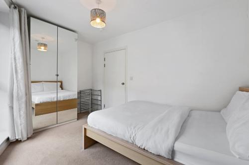 a white bedroom with a bed and a mirror at London Dockside Apartment in London