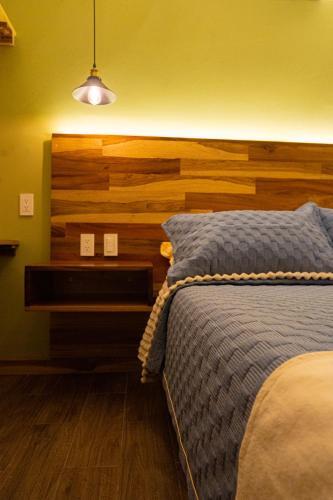 a bedroom with a bed with a wooden headboard at Hotel Casa Tsumbak in Tuxtla Gutiérrez