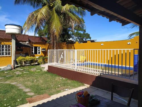 a yellow house with a white fence and a palm tree at Casa De Praia Baptista Resort Jacaraípe in Serra