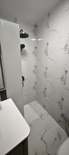 a bathroom with white marble walls and a shower at Chambres d'Hôtes Centre Ville in Dakar