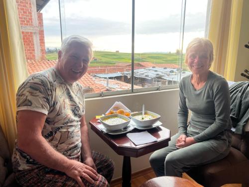 an older man and a woman sitting in a room with a table with a meal at Hotel Chinchero Boutique & Tours in Chinchero