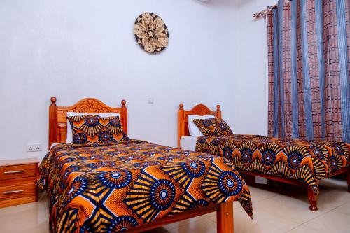 a bedroom with two beds and a clock on the wall at Isange Paradise Resort in Ruhengeri