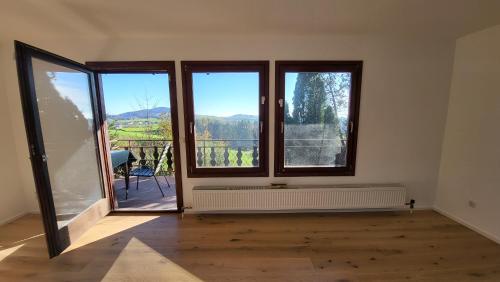 an empty room with two windows and a balcony at Cottage Alpenblick in Gramastetten