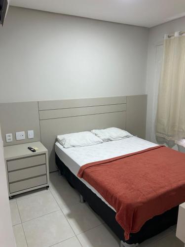 a bedroom with a bed with a red blanket at Flat completo com linda vista in Palmas