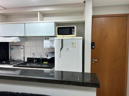 a kitchen with a microwave on top of a refrigerator at Flat completo com linda vista in Palmas