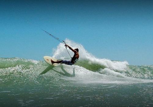 a man riding a wave on a surfboard in the ocean at Pousada Altas Horas Icaraizinho in Icaraí
