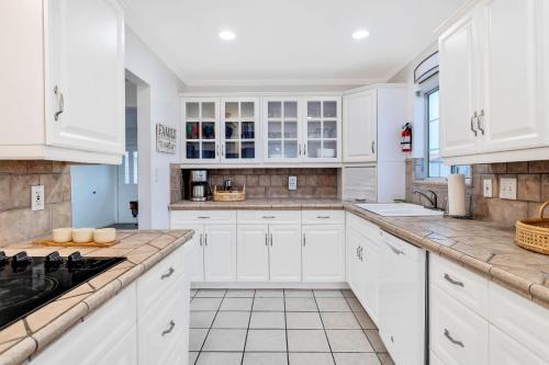 a white kitchen with white cabinets and a sink at 6 Mi to Joshua Tree Home with Outdoor Oasis and View! in Twentynine Palms