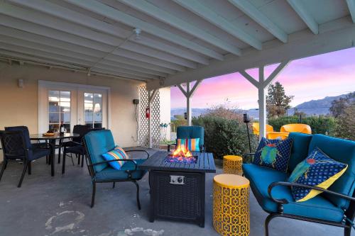 a patio with blue chairs and a table with a fireplace at 6 Mi to Joshua Tree Home with Outdoor Oasis and View! in Twentynine Palms