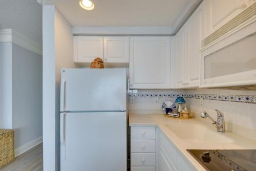 a kitchen with white cabinets and a refrigerator at Daytona Beach Studio Condo with Ocean Views! in Daytona Beach