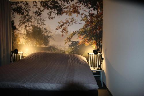 a bedroom with a bed with a tree mural on the wall at Vakantiehuis Weideblik in Biezenmortel