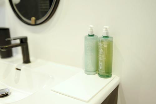 deux bouteilles de liquide vert posées sur un lavabo de salle de bain dans l'établissement Le Dantzig - Paris Expo, métro Convention, à Paris