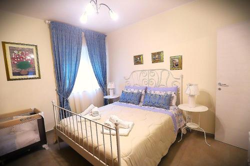 a bedroom with a bed with blue curtains and a window at Villa Biniritta in Villaggio San Leonardo