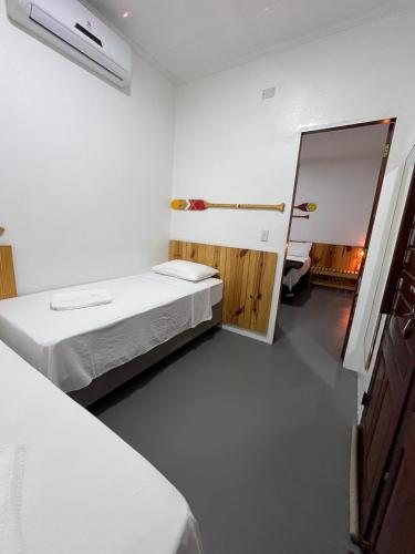a white room with two beds and a mirror at Pousada Altas Horas Icaraizinho in Icaraí