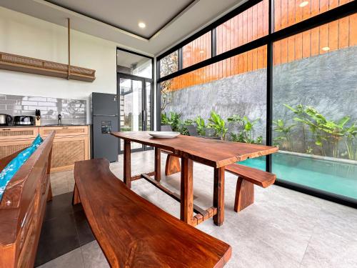 a dining room with a wooden table and a bench at Kawul Harvest Palace Tanah Lot in Tanah Lot