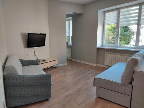 a living room with two couches and a flat screen tv at Студія поряд з замком Любарта in Luts'k