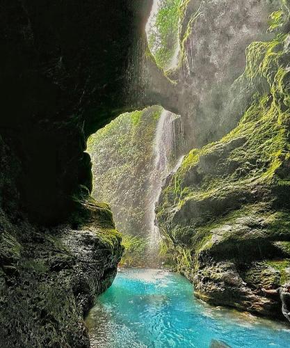 a waterfall in a cave next to a river at Vistas Paraiso San Carlos in Venecia