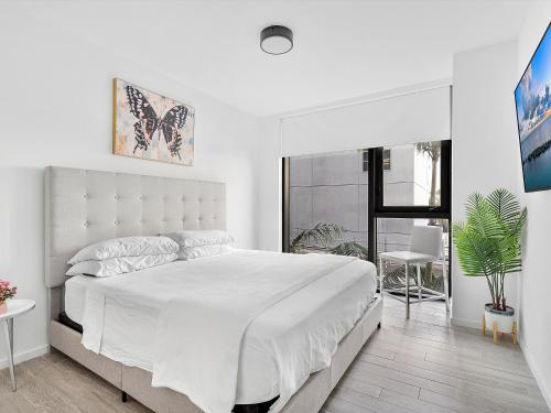 a white bedroom with a large bed and a window at X Lounge III-Modern Corner Residence in Miami