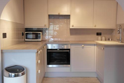 a kitchen with white cabinets and a microwave at Ashford House 2 bedroom Apartment 'outdoor bathing tub' in Fylingthorpe