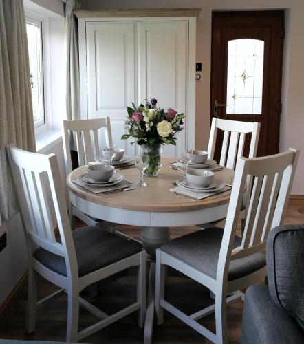 a dining room table with a vase of flowers on it at Ashford House 2 bedroom Apartment 'outdoor bathing tub' in Fylingthorpe