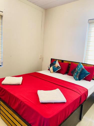 a large red and white bed with red and blue pillows at AquaTerra Comfy stay Varkala beach in Varkala