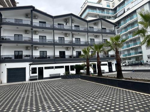 a large building with palm trees in front of it at Molla Hotel Restorant in Shëngjin