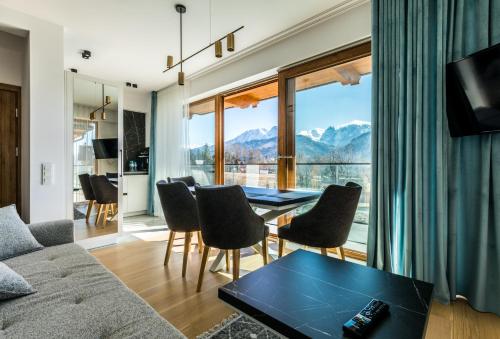 a living room with a table and chairs and a large window at Apartamenty Krokusowa Dolina in Kościelisko
