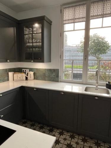 d'une cuisine avec des placards noirs, un évier et une fenêtre. dans l'établissement Villa 1920 rénovée, à Guérande