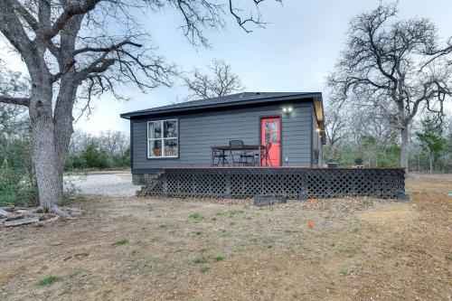 a tiny house with a red door in a yard at Private Deck and Forest Setting Waelder Cabin! in Waelder