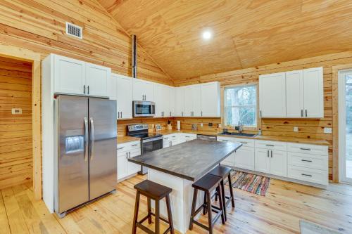 a large kitchen with a table and a refrigerator at Private Deck and Forest Setting Waelder Cabin! in Waelder