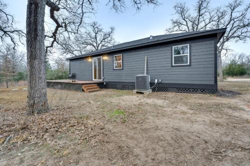 a gray house with a bench and a tree at Private Deck and Forest Setting Waelder Cabin! in Waelder