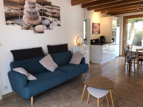 un salon avec un canapé bleu et une cuisine dans l'établissement Maison en bord de mer et lisière de forêt, à La Tranche-sur-Mer
