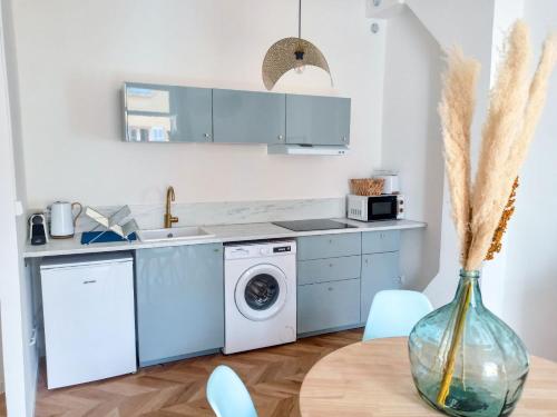 une cuisine avec une machine à laver et un vase sur une table dans l'établissement Lumière dorée, à Hyères