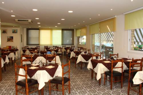 Hotel Primula في ليدو دي سافيو: مطعم بطاولات وكراسي مع طاولة قماش بيضاء
