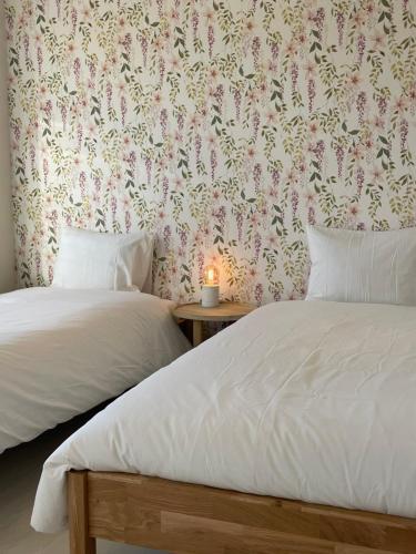 two beds in a room with a wallpaper with flowers at Vakantiehuis 'Dune' de panne in De Panne