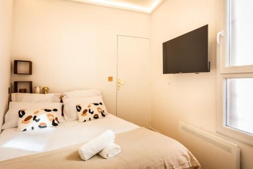 a bedroom with a bed with cow pillows and a flat screen tv at Appartement Raffiné avec Jacuzzi et AC - 6P in Paris