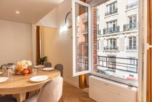 une salle à manger avec une table et une grande fenêtre dans l'établissement Appartement Raffiné avec Jacuzzi et AC - 6P, à Paris