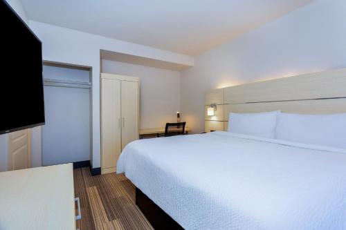 a bedroom with a white bed and a flat screen tv at Holiday Inn Express-International Drive by IHG in Orlando