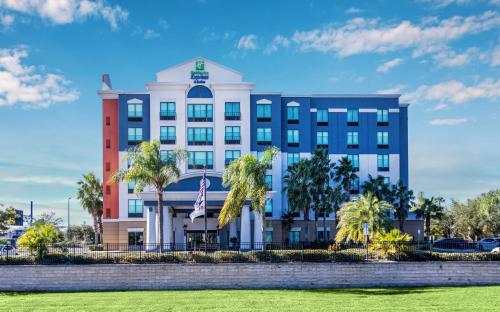 a large white building with palm trees in front of it at Holiday Inn Express-International Drive by IHG in Orlando