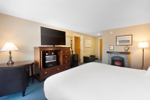 a bedroom with a bed and a tv and a fireplace at Fireside Inn & Suites Gilford in Gilford