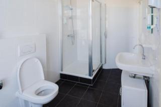 a bathroom with a toilet and a shower and a sink at Hotel Grand Cafe Deight in Zandvoort