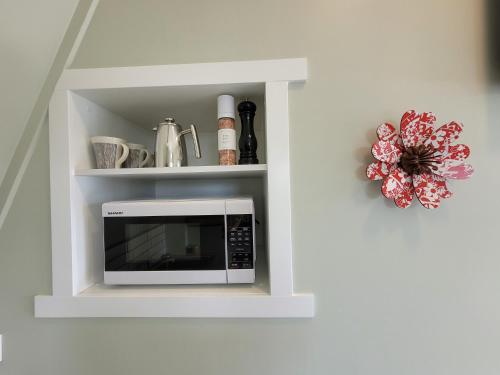 a microwave in a white cabinet with a shelf at Riverside Retreat in Whangarei
